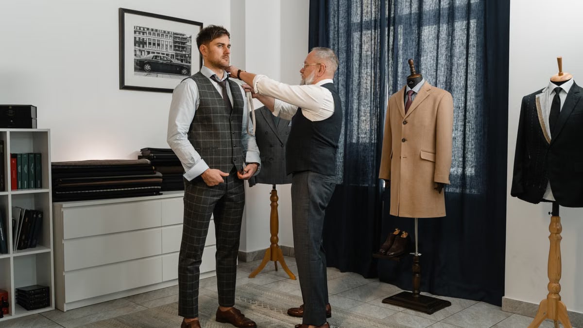 Experienced tailor adjusting a young man's stylish suit in a sophisticated atelier setting.